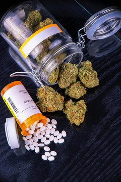Cannabis buds and prescriptions pills over black surface - medical marijuana concept