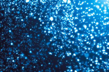 Abstract bokeh or glitter lights on blue  background. Circles and defocused particles. Design template