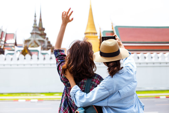 Two girlfriends taking photos while traveling to Grand- Palace in Bangkok,Thailand 