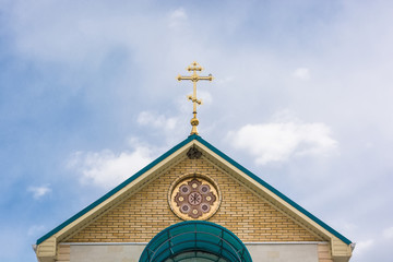 Orthodox cross at church rooftop against blue sky