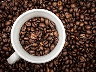 Cup of coffee beans on coffee background
