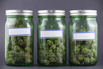 Cannabis glass jars over grey background - medical marijuana dispensary concept - obrazy, fototapety, plakaty