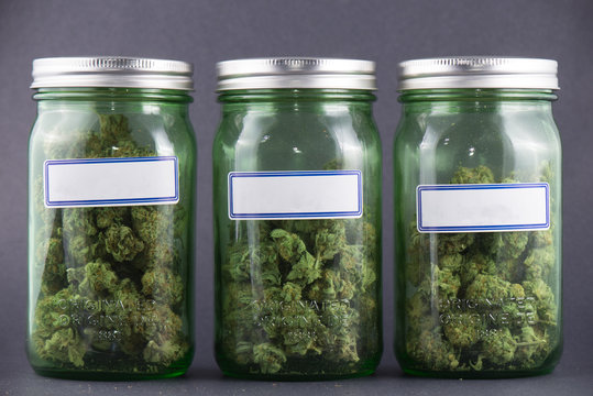 Cannabis glass jars over grey background - medical marijuana dispensary concept