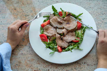Healthy food. Salad from arugula, tomatoes and roast beef.
