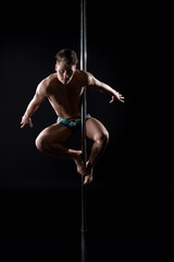 Young fair athletic man exercising on pylon