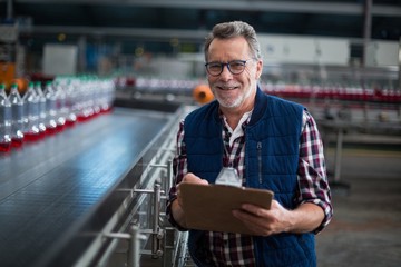 Portrait of smiling factory worker standing with a clipboard