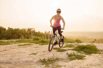 Girl on mountain bike rides on the trail on a beautiful sunrise.