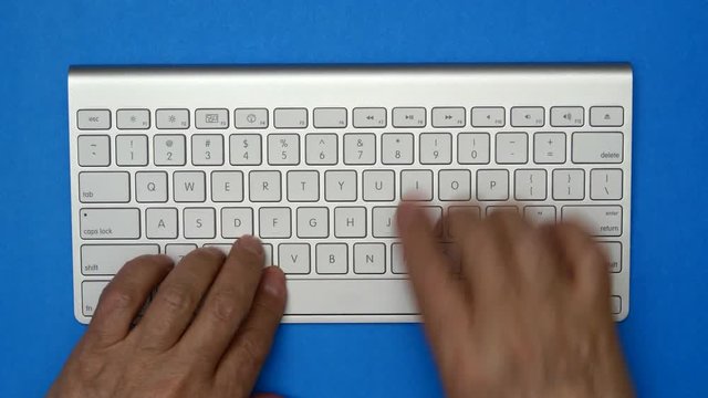 Elderly Man Is Typing On A Keyboard. Blue Background.