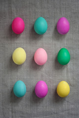 Pattern of Rows of colored easter eggs grey linen textured background. Easter web Background. Group of colored painted eggs. Happy Easter celebration concept. Template mock up with copy space for text
