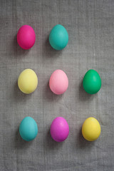 Pattern of Rows of colored easter eggs grey linen textured background. Easter web Background. Group of colored painted eggs. Happy Easter celebration concept. Template mock up with copy space for text
