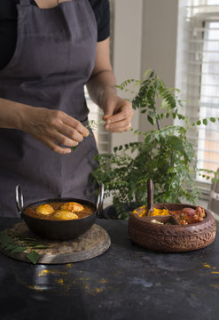 Woman preparing boiled egg curry dish 