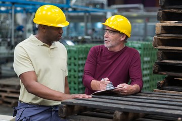 Factory workers discussing with a clipboard 