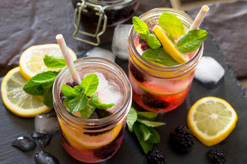 Refreshing summer drink with blackberries, lemon and mint on a stone background. The concept of eating vegetarians, fresh vitamins, a homemade refreshing fruit drink.