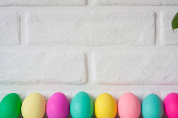Easter colored eggs put in line on table against white brick wall background. Cute Easter celebration decor. Copy space for text. Happy Easter card. Easter concept. Web banner background. Web Banner.