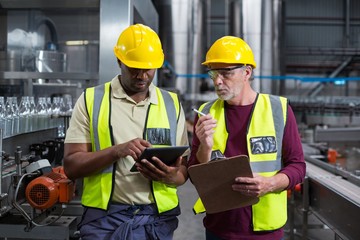 Two factory workers with clipboard and tablet 