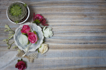 Shabby artificial Pink white beige flowers and lace decor on beautiful wooden table desk with shadow background, free copy space for text on paper note. Shabby chic interior office holiday decorations