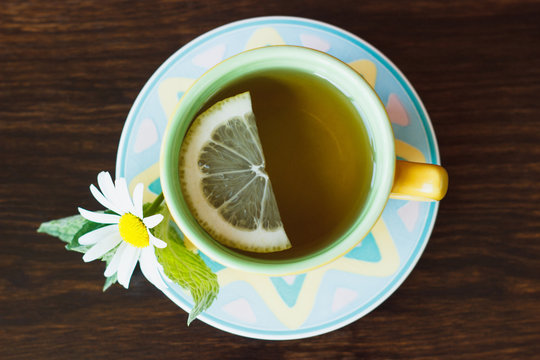 Cup of herbal tea with camomile and mint leaves on the wooden background
