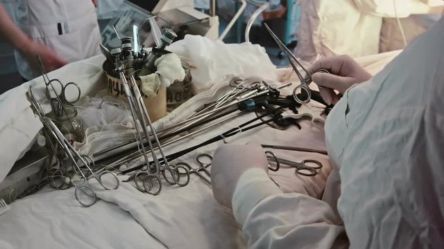 Operating. A nurse prepares the tools for Ssrgery. 