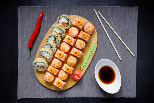 Traditional food. Japanese food - sushi rolls, sauce, pepper and chopsticks on a dack background. Top view. Flat lay