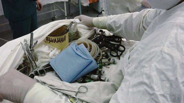 Operating. A nurse prepares the tools for Ssrgery. 