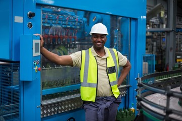 Fototapeta na wymiar Smiling factory worker standing near machine control cabinet