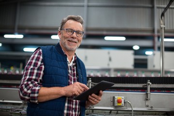 Smiling factory worker using digital tablet in the factory - Powered by Adobe