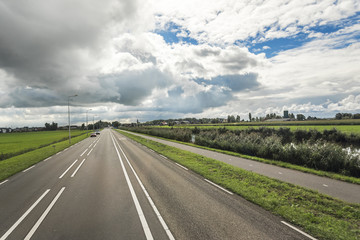 Country road with beautiful markings, against a contrasting cloudy sky.