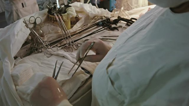 Operating. A nurse prepares the tools for Ssrgery. 