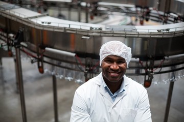 Smiling factory engineer standing in bottle factory