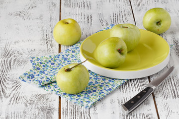 Fresh greenish apples in a dish on a rustic background.