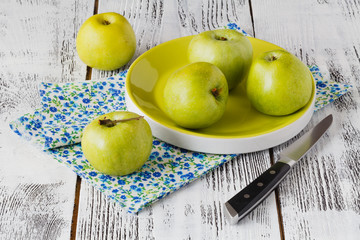 Fresh greenish apples in a dish on a rustic background.