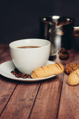 cup with a drink, biscuits and coffee beans in a saucer