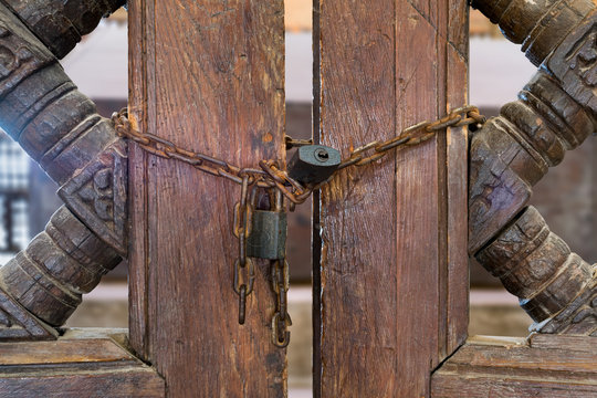 Old rusted padlocks and rusted chain on a half closed wooden interleaved double door