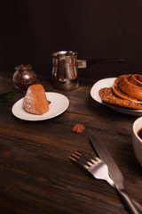 a cake and a cinnamon roll, an iron ladle and a jar with coffee beans