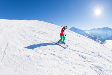 Fototapeta na wymiar Little skier walking down the hill at sunny day