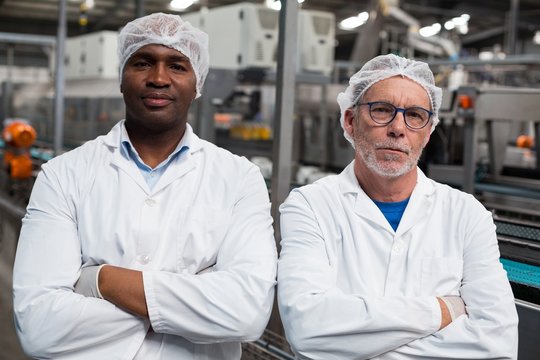 Portrait of two factory engineers standing with arms crossed
