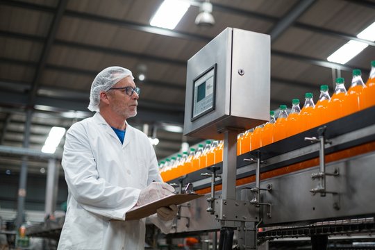 Factory engineer maintaining record on clipboard in factory