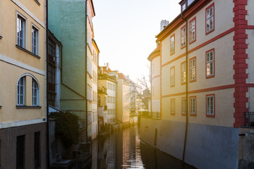 Fototapeta na wymiar Beautiful view of a street with old water mill in a canal in center of Prague at sunrise. Czechia