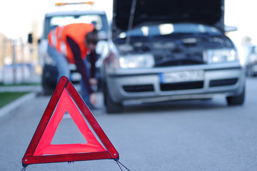 Mann in Warnweste bei seinem liegengebliebenen Auto  