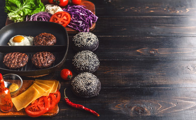 Ingredients for a black burger on a wooden surface