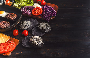 Ingredients for a black burger on a wooden surface