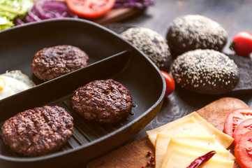 Ingredients for a black burger on a wooden surface