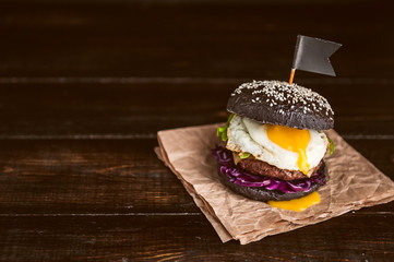 Delicious and juicy black burger with a large cutlet of meat on a black background