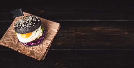 Delicious and juicy black burger with a large cutlet of meat on a black background