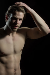 Fototapeta na wymiar Attractive naked man touches his hair. Handsome guy with a beautiful body in the studio on a black background