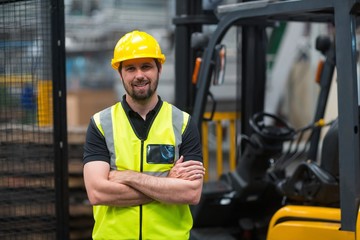 Factory worker standing with arms crossed in factory