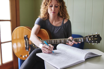 a woman with a guitar, writing music.