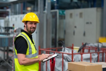 Portrait of smiling factory worker using a digital tablet