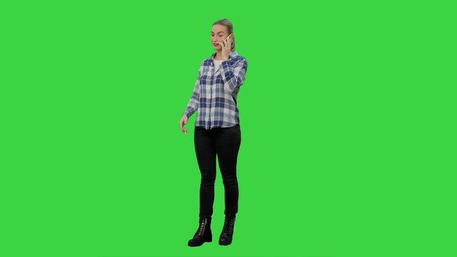 Young woman in casual talking gossips via cellphone on a Green Screen, Chroma Key.