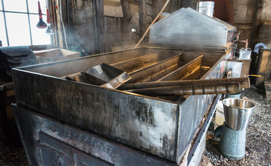steam rising off of boiler evaporating  maple tree sap to make maple syrup in sugar house, an early...